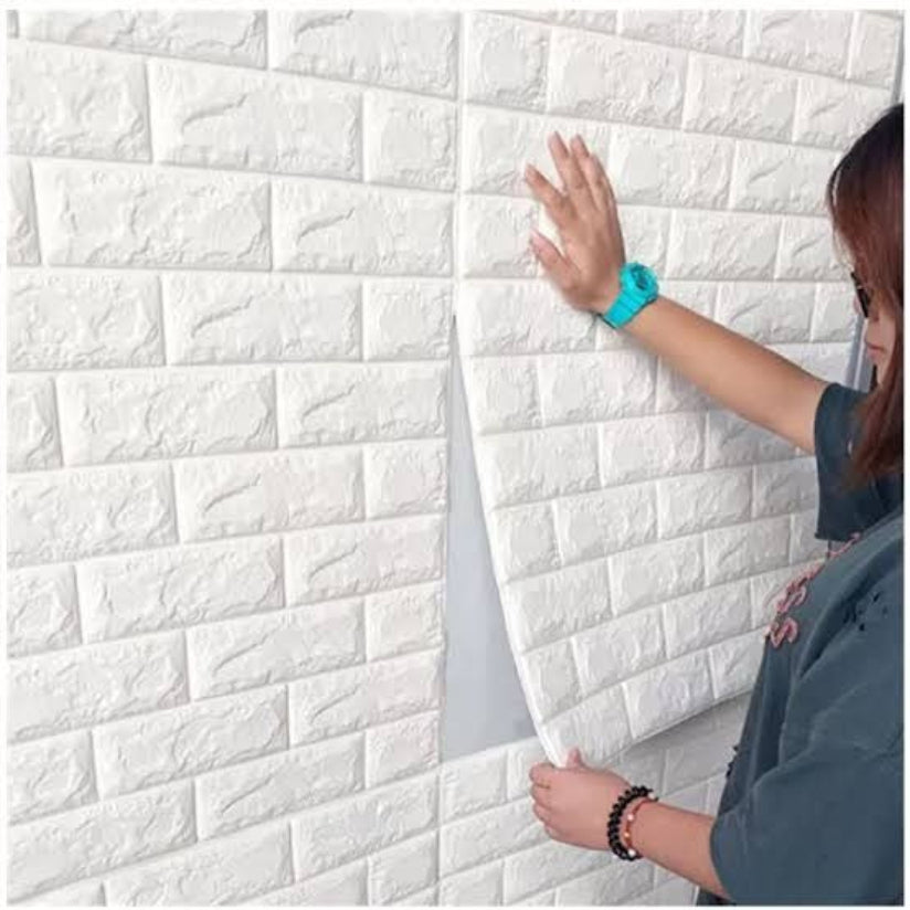 Person applying white 3D brick-patterned wall panel to a wall.