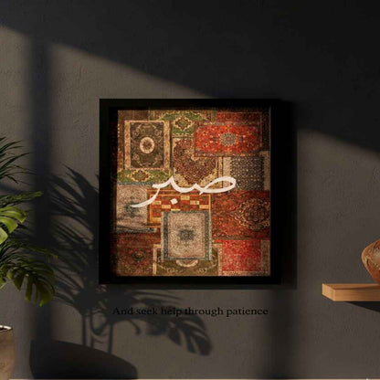 Framed artwork with Arabic calligraphy on a dark wall, accompanied by a plant and vase.