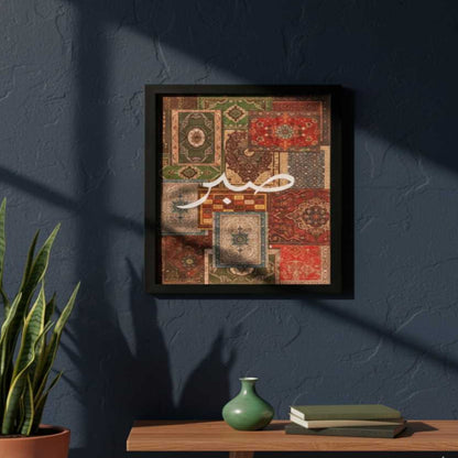 Framed artwork with a patchwork design and Arabic text on a dark blue wall.